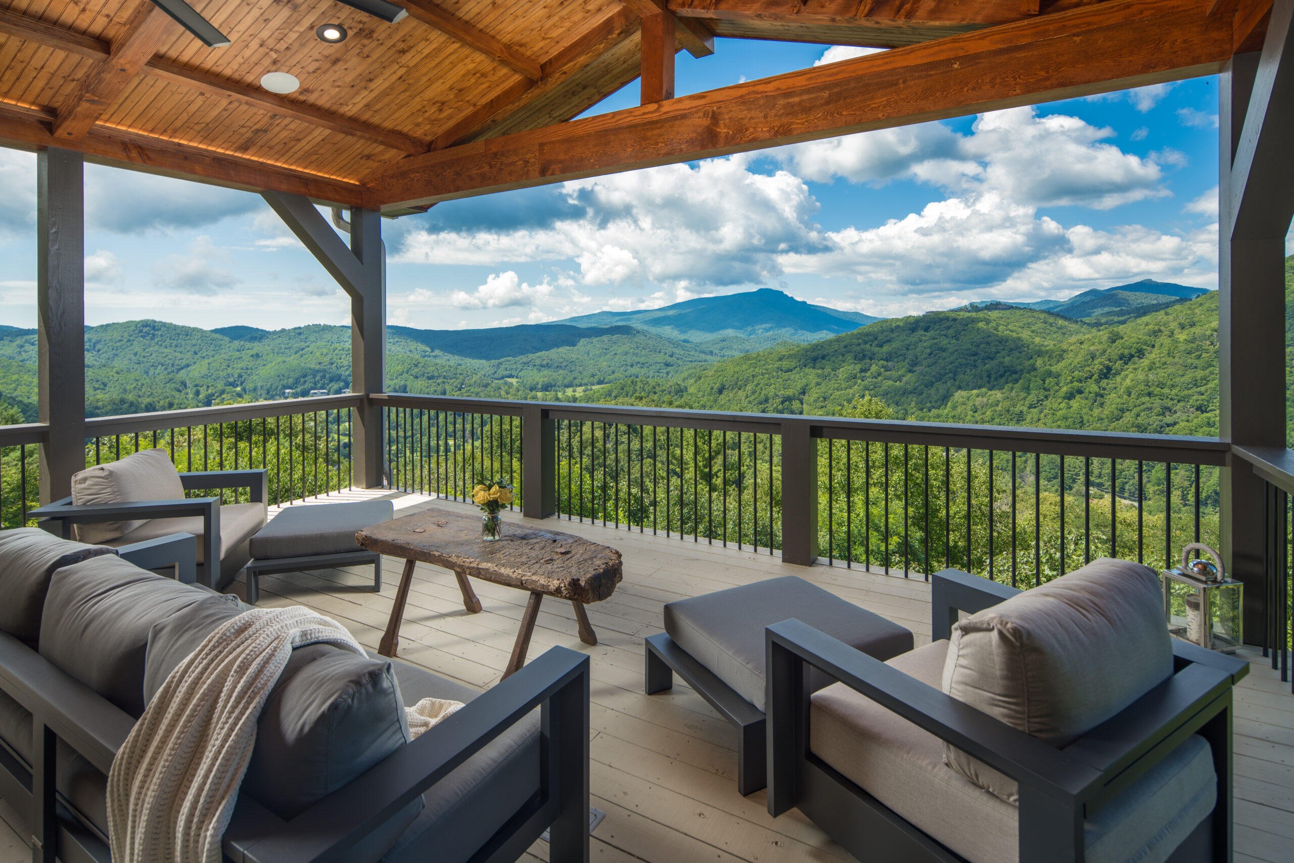 Covered deck with outdoor seating overlooking green mountains