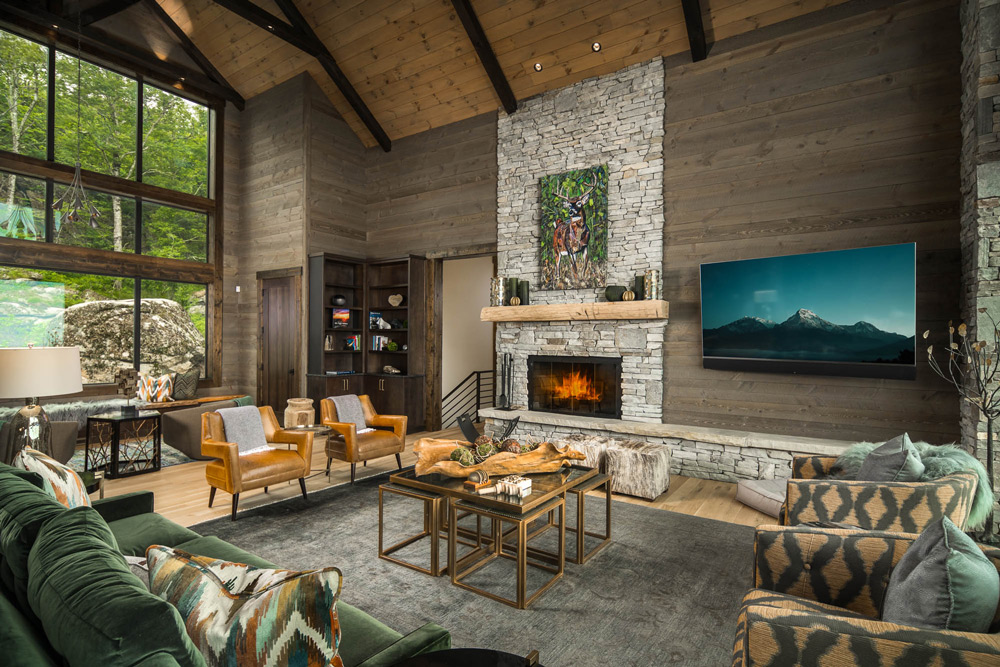Living room with cathedral ceilings and large wall of windows overlooking nature.