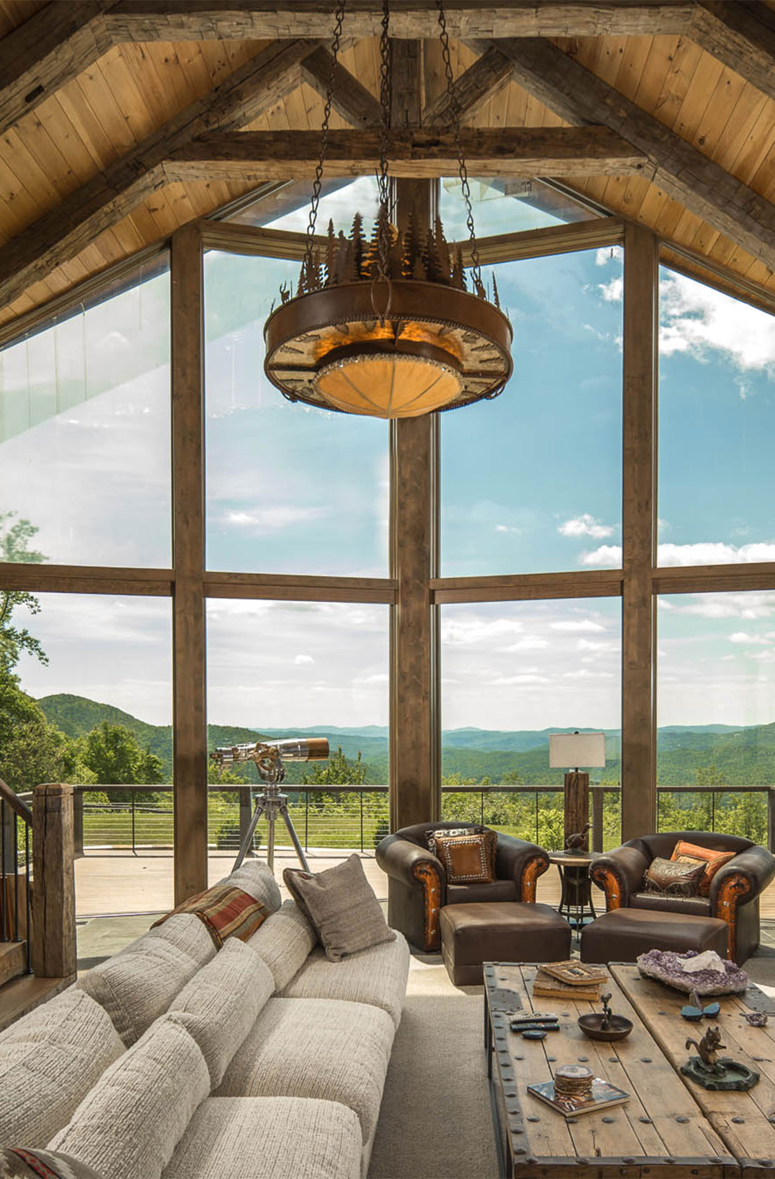 Rustic style living room with wall of windows overlooking the mountain range.